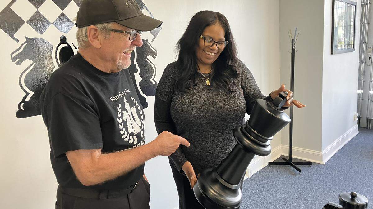Jessica Rosario from Warriors Inc. shows a chess piece to Mike Taninecz of Warren at the Chess House.