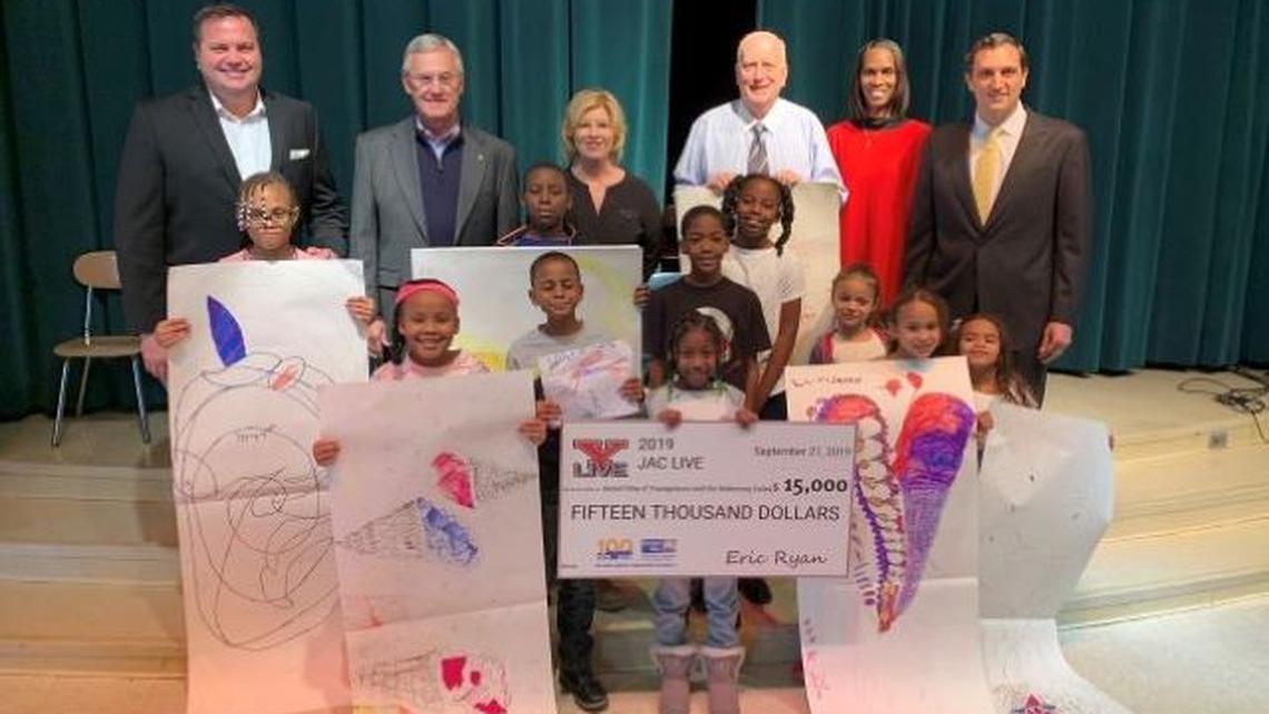 Standing behind Harding Elementary School students and participants in the United Way of Youngstown and the Mahoning Valley’s Success After 6 program are, from left, Eric Ryan, JAC Live president and CEO; Jim Tressel, president of Youngstown State University; Stacia Erdos, vice president of strategic planning for the United Way of Youngstown and the Mahoning Valley; Bob Hannon, president of the United Way of Youngstown and the Mahoning Valley; Teri J. Coward, Harding Elementary School principal; and Eddie Muransky, president of Rise Pies. (Contributed photo)
