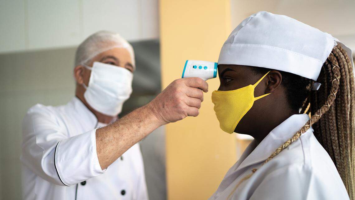 A restaurant chef tests an employee's temperature amid the COVID-19 pandemic.