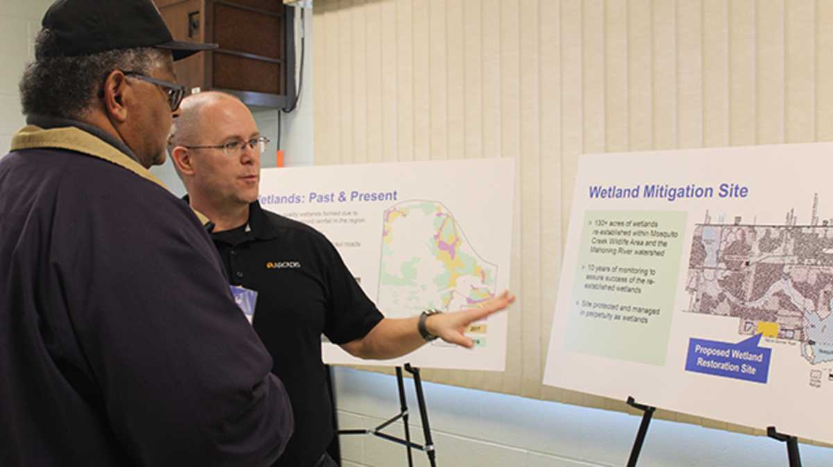 Vinnie Tremante, a senior ecologist with environmental consulting firm Arcadis, right, talks with skilled laborer Carlton Ingram about a map that shows how wetland impact will be mitigated at the site of a proposed battery cell plant during a public meeting hosted Thursday, March 5, 2020 in Lordstown. (Justin Dennis | Mahoning Matters)