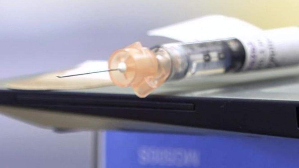 A hypodermic syringe lies on a table.
