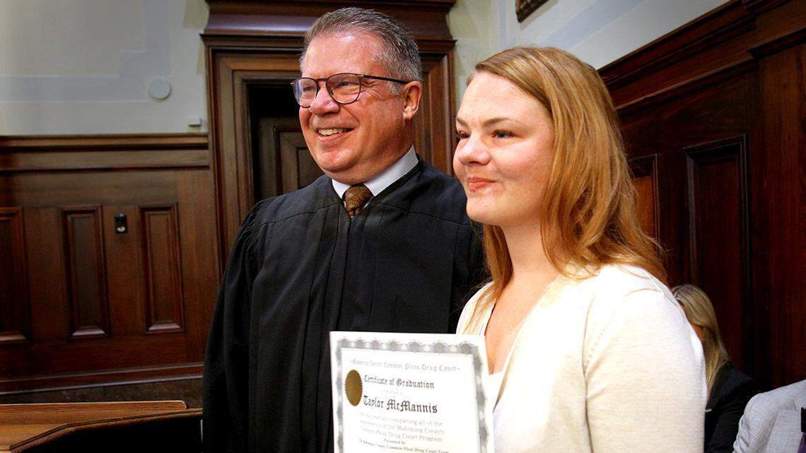 Taylor McMannis, a graduate of Mahoning County’s drug court (right), poses for a photo after receiving her diploma from Judge John M. Durkin (left) during a ceremony at the Mahoning County Courthouse in Youngstown, Ohio, on April, 27, 2022.