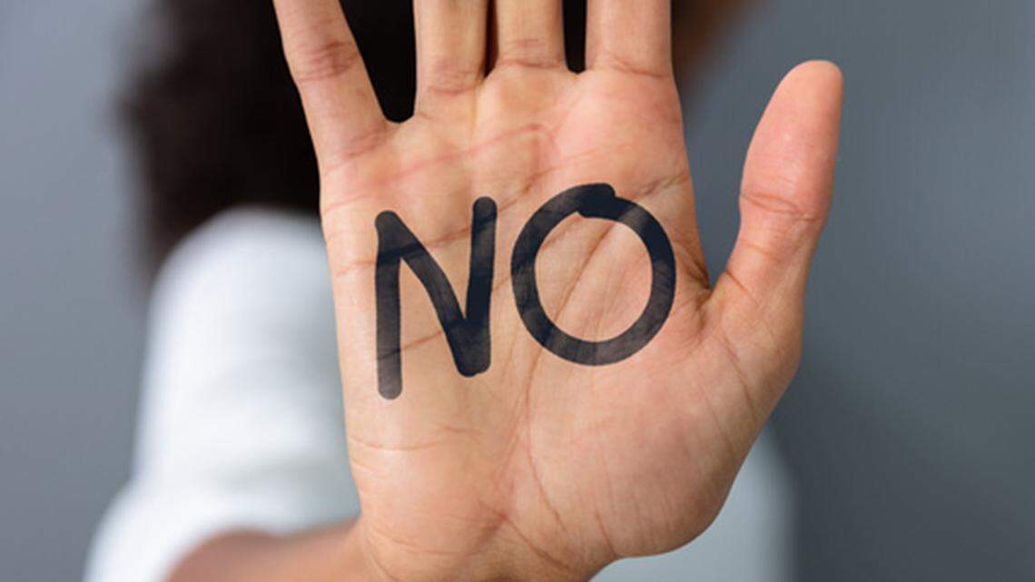 A woman's hand the word "No" written on an open palm.