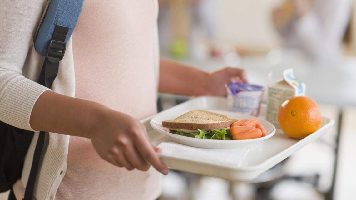 Student walks to her seat at lunch at school.