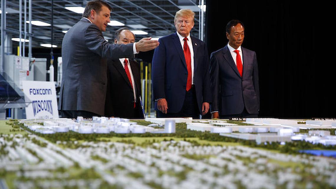 In this June 28, 2018 photo, President Donald Trump takes a tour of Foxconn with Foxconn chairman Terry Gou, right, and CEO of SoftBank Masayoshi Son in Mt. Pleasant, Wis.  Foxconn Technology Group will qualify for up to $80 million in state tax incentives under a new contract agreed to on Tuesday, April 20, 2021 that downsizes the scale of credits as the size of the envisioned manufacturing facility has also shrunk. Gov. Tony Evers announced details of the new contract.  (AP Photo/Evan Vucci, File)