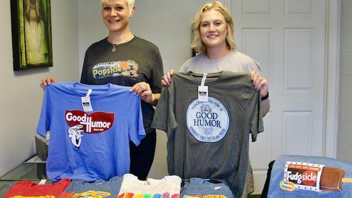 New Dawn Designs owner Linda Barton (in black) and her sales manager Abby Scoville show the latest T-shirt designs. (Bob Yosay/Mahoning Matters)