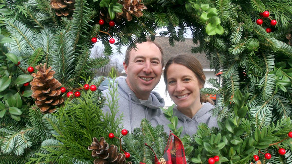 Ian and Tara Fodor, owners of Fodor Tree Farm in Poland, are framed in a wreath at their farm. (William D. Lewis)