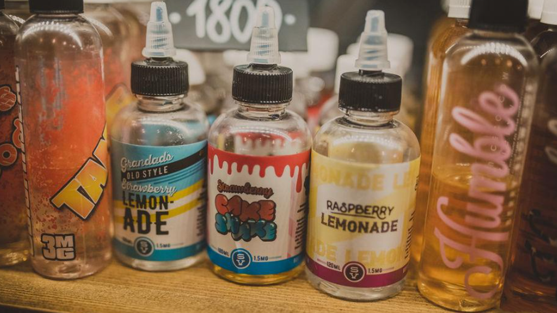 E-cigarette flavors on a shelf at a vape shop.