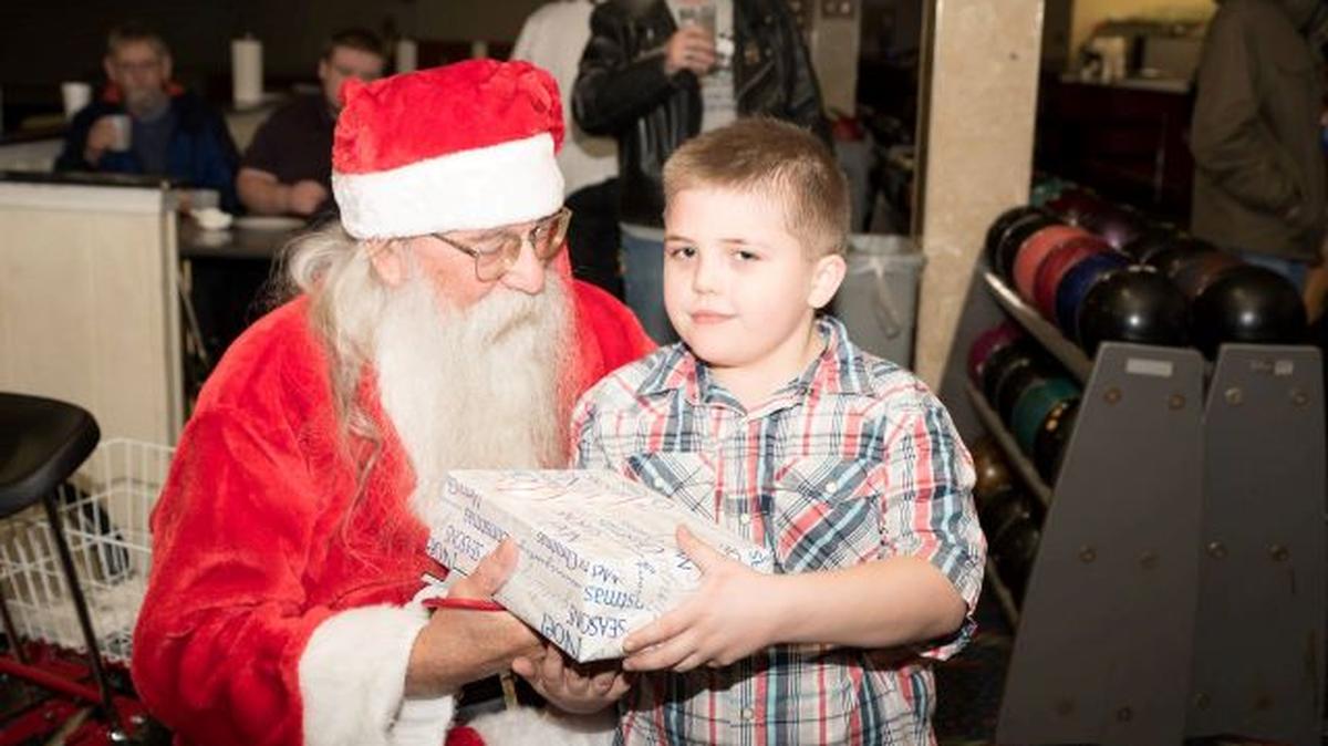 A young boy receives a gift from Santa at a past Holiday Autism Family Gift Presentation & Bowling Party. (Contributed photo)