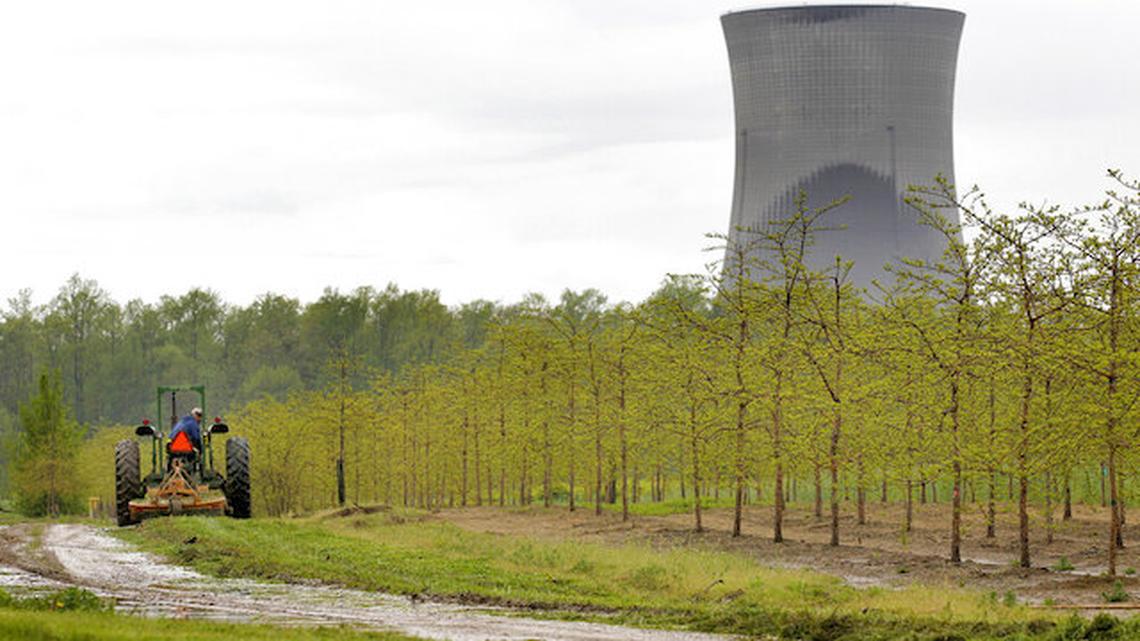 In this May 18, 2011, file photo, a worker is seen in the area surrounding a tree farm in North Perry, near the two cooling towers of the Perry Nuclear Power Plant looming in the background. (AP Photo/Amy Sancetta, File)