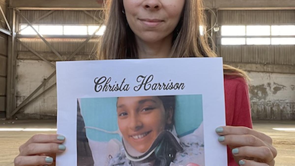 Penguin City Brewery co-owner Aspasia Lyras-Bernacki holds a poster promoting a fundraiser for shooting victim Christa Harrison.
