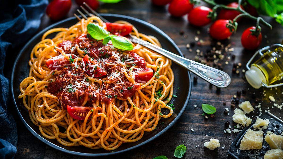 A plate of pasta with red sauce and a fork.