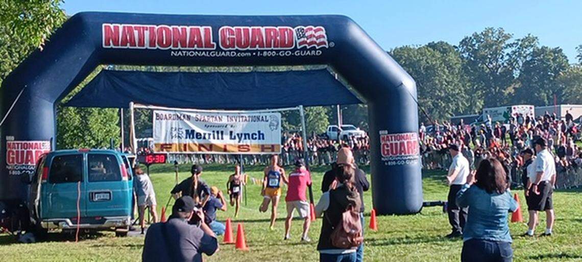 A top finisher crosses the finish line during Saturday’s Boardman Spartan Invitational held before thousands of fans on the grounds of Boardman High School.