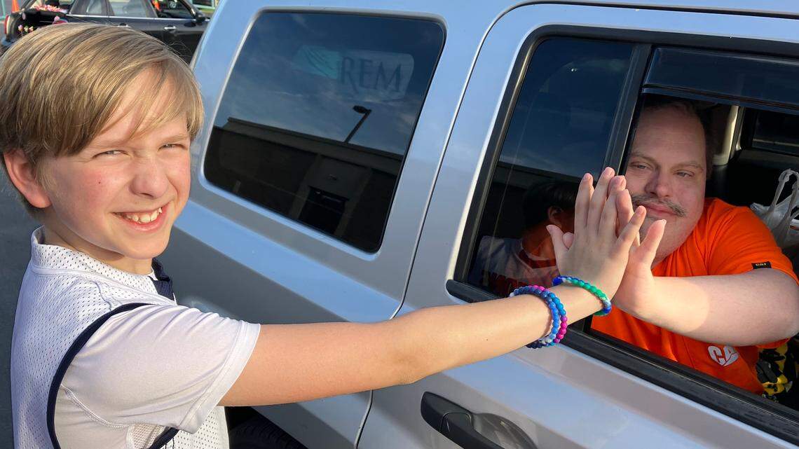 Austintown Fitch sixth-grader Cooper Bilas gives Canfield resident Terry Bacha a high-five during the Reverse Parade at at Mahoning County Board of Developmental Disabilities in Austintown.