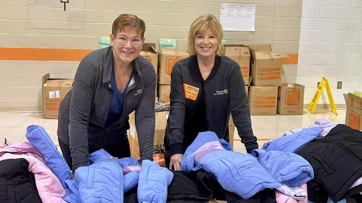 Committee Co-Chairs Stacia Erdos (left) and fellow Rotarian volunteer Aundrea Cika Heschmeyer prepare to fit students with brand-new winter coats at Harding Elementary.