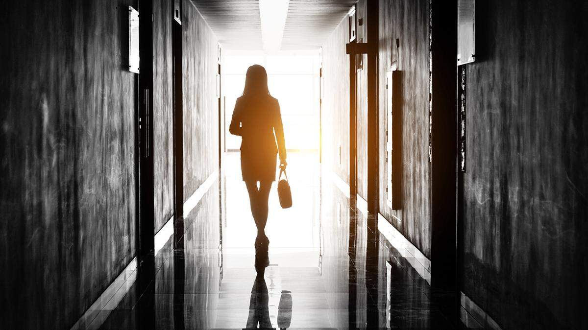 A businesswoman in a suit exiting an office with briefcase in-hand.