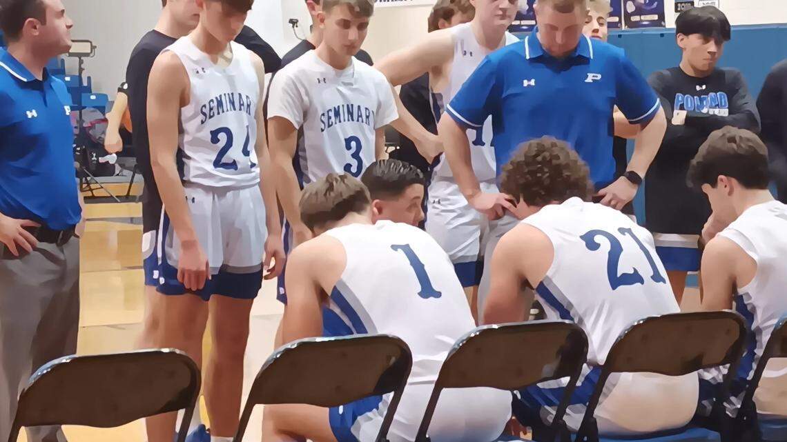 Poland head coach Eric Fender, bottom, second from left, talks strategy with his team during a timeout in Saturday night’s game against visiting Boardman in the 11th annual United Way Holiday Basketball Classic held at Poland. 