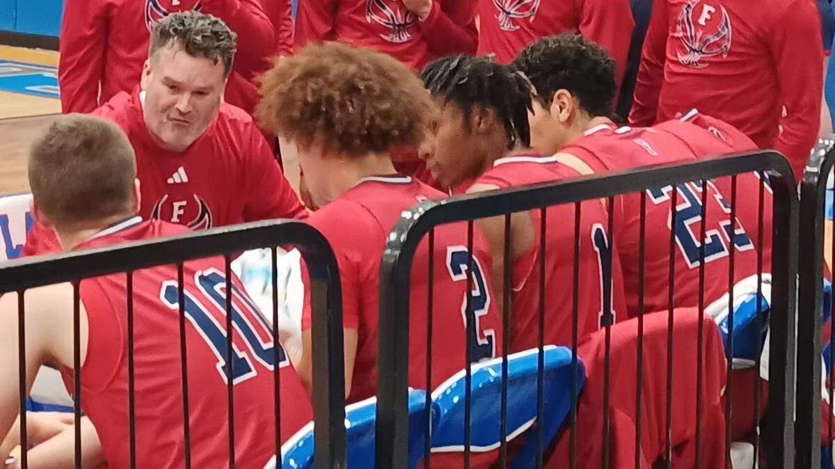 Austintown Fitch boys’ basketball coach Brian Beany, top left, talks to his team in a timeout during Friday night’s game at Lake.