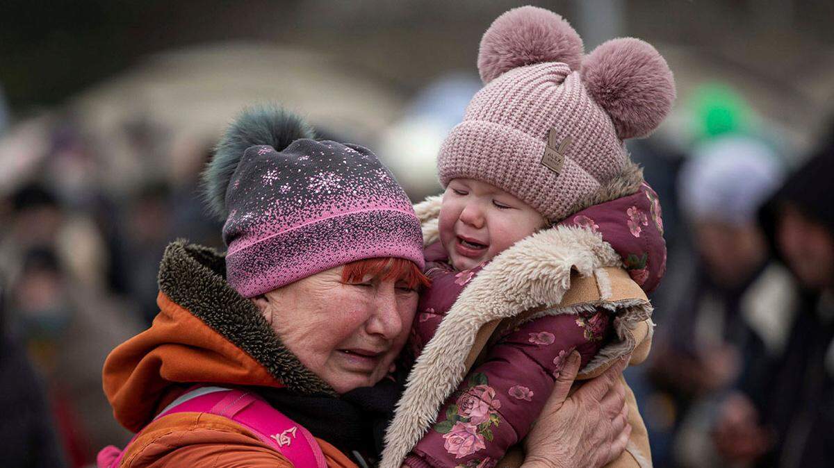 A woman holding a child cries after fleeing from Ukraine and arriving at the border crossing in Medyka, Poland.