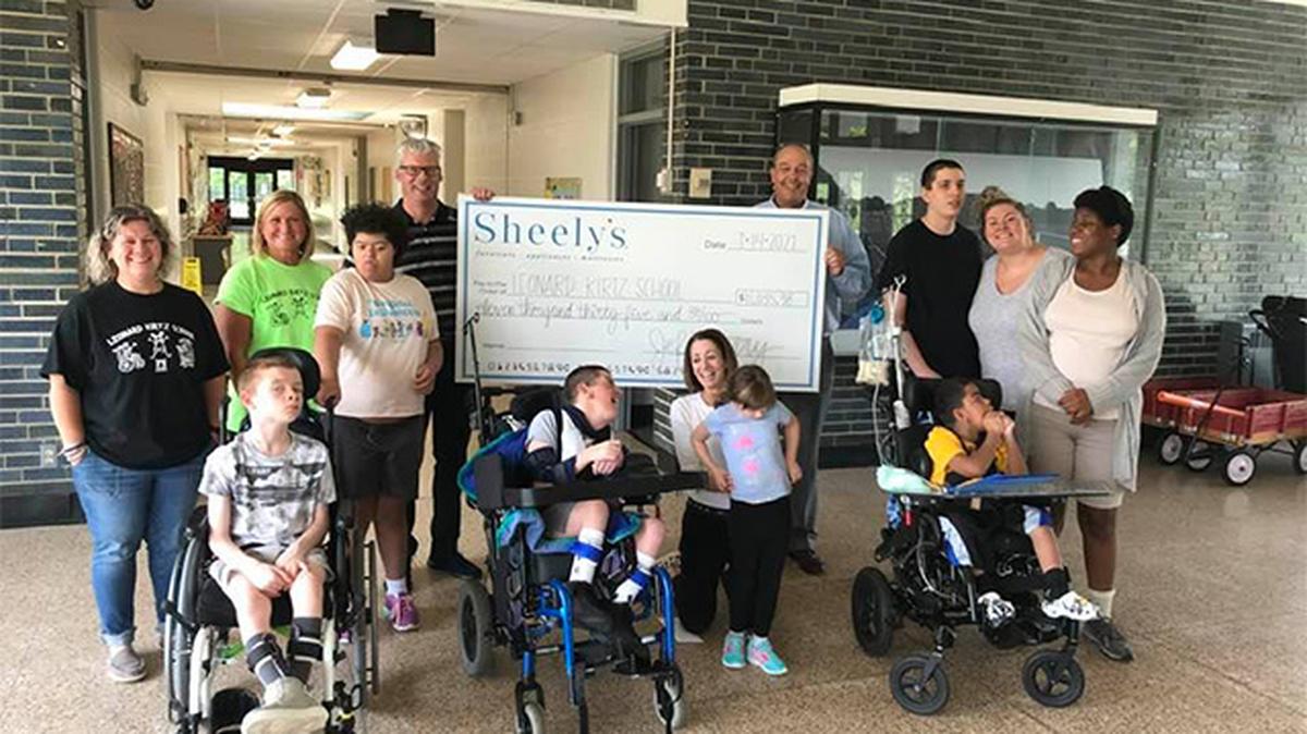 Lance Romeo, Sheely’s Furniture and Appliance buyer and principal owner, and Jeff Curry, general manager and principal owner, present a check to the Mahoning County Board of Developmental Disabilities and the Leonard Kirtz Playground Project. Also pictured are staff and students of the Leonard Kirtz School. (Contributed photo)