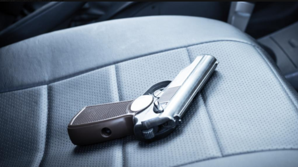 Gun laying on a car seat.