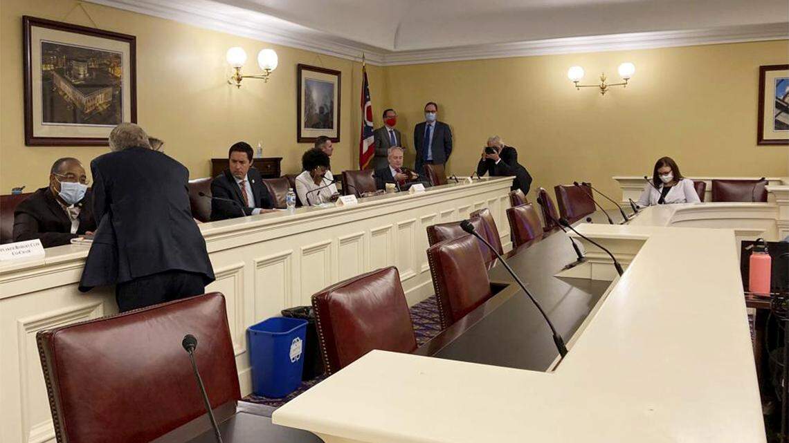 In this Sept. 15, 2021, file photo, Gov. Mike DeWine, foreground, speaks to state Sen. Vernon Sykes, seated, the co-chair of the Ohio Redistricting Commission, as other members of the panel prepare for a meeting at the Ohio Statehouse in Columbus.