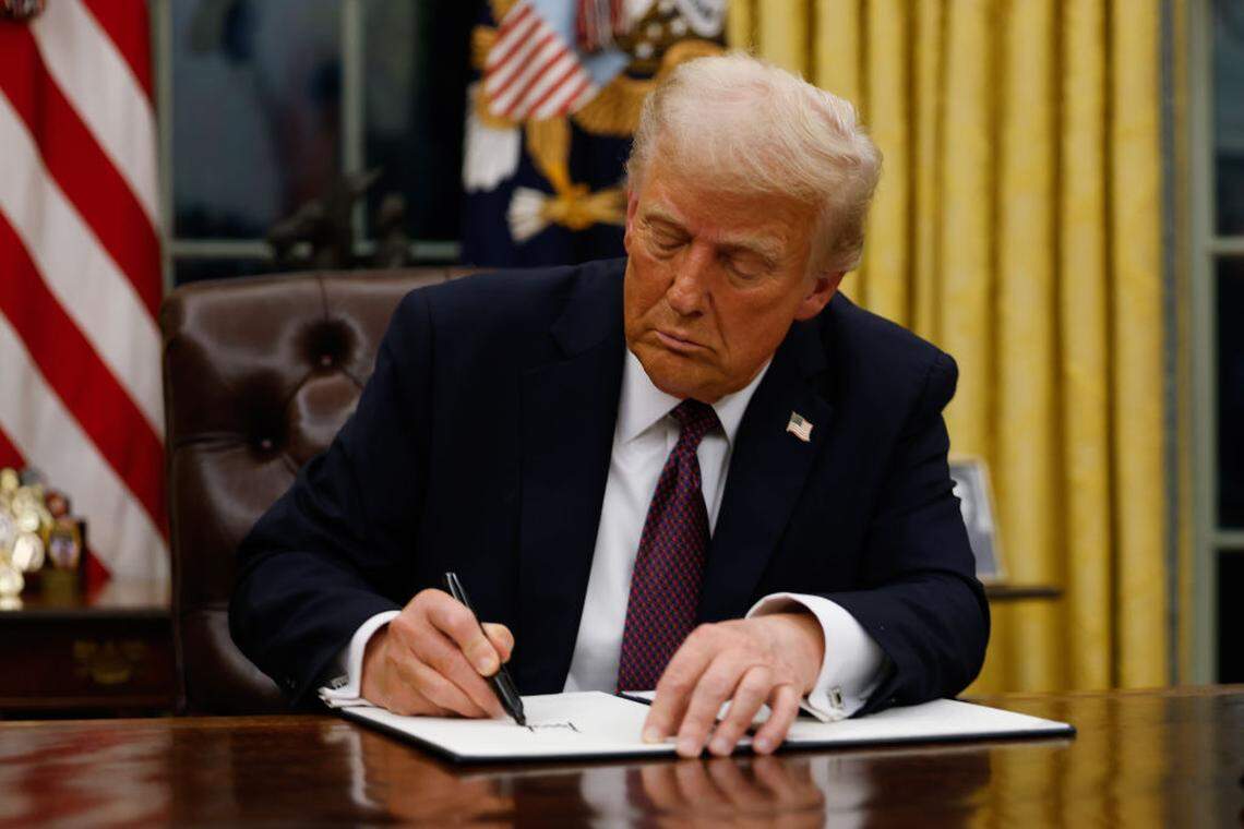 President Donald Trump signs executive orders in the Oval Office of the White House.
