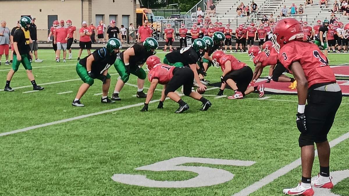West Branch quarterback Jeremiah Thomas, left, prepares to take the shotgun snap as members of the Sruthers defense, right, dig in during Friday’s high school football scrimmage in Struthers. The two team’s first units tied, 2-2. Photo/Mike Brown