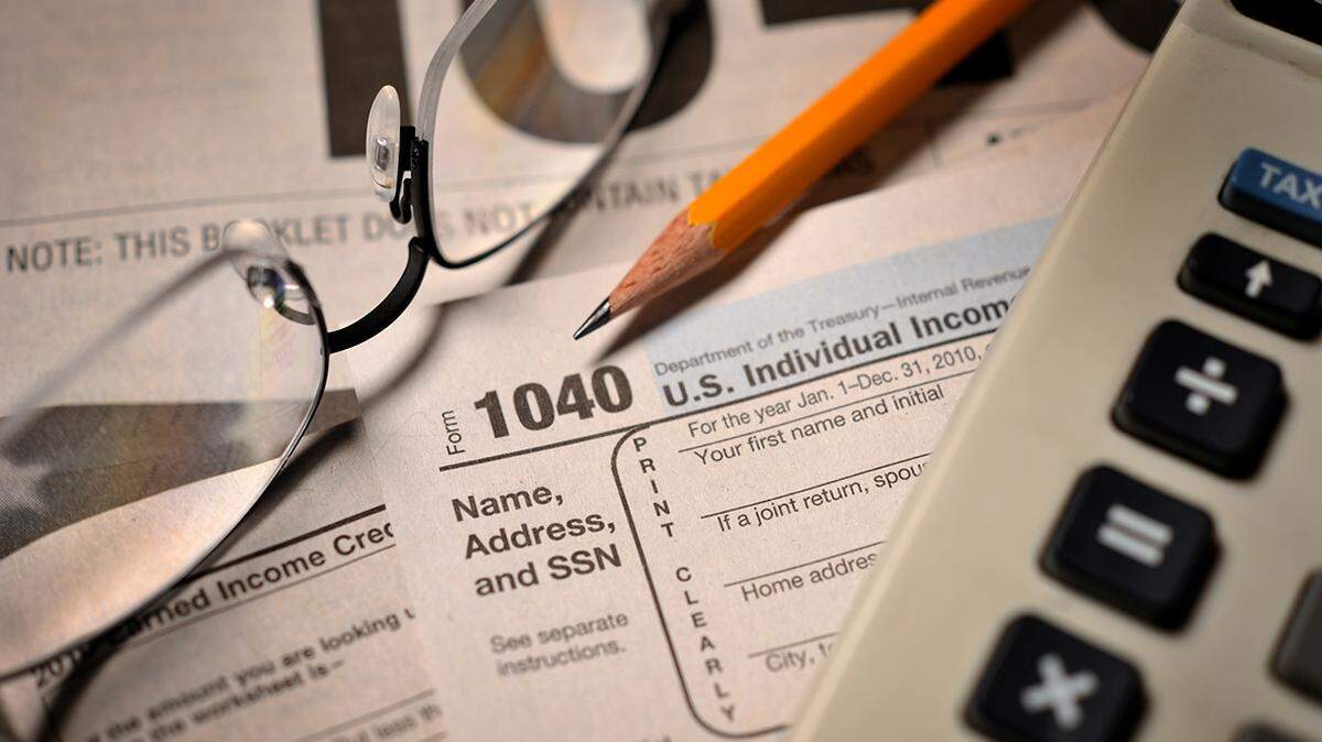 Shown here are an IRS Form 1040 for income taxes, a pair of glasses and a calculator.