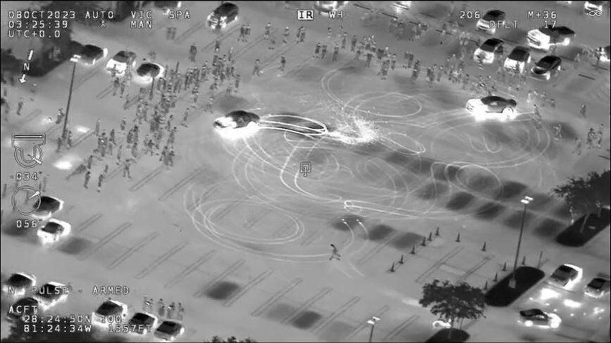 An infrared image shows cars doing burnouts in a parking lot.