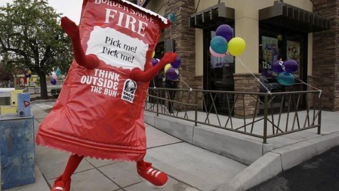 This Dec. 13, 2010, photo shows a Taco Bell restaurant opening with a person in a taco sauce outfit outside in Mountain View, Calif. The taco chain is now encouraging customers to mail in their used hot sauce packets as part of a new recycling initiative with TerraCycle. (Paul Sakuma | AP Photo)