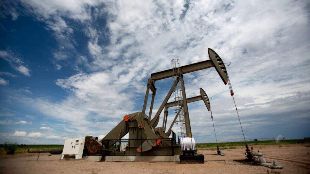 Pumpjacks on the horizon underneath a partly cloudy beautiful sky. These pieces of equipment are crucial to oil field and fracking operations