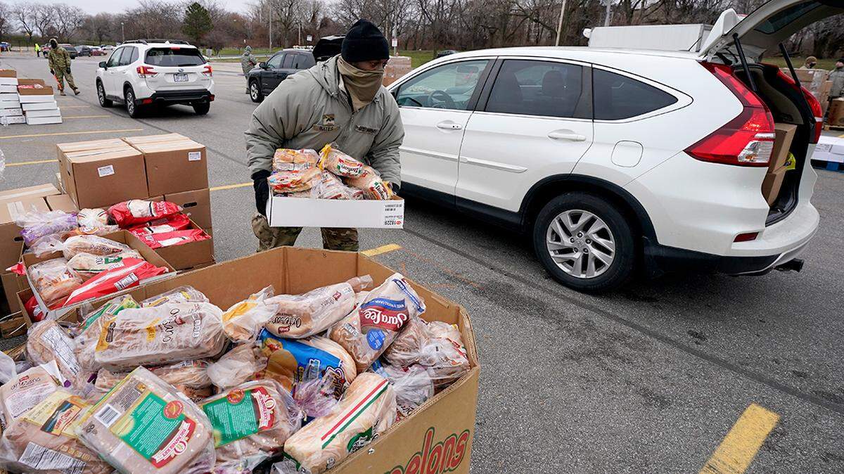 FILE - Corpl. James Bates carries a box of groceries to a car at a food bank distribution by the Greater Cleveland Food Bank, Thursday, Jan. 7, 2021, in Cleveland. Food banks across America say these economic conditions are pushing demand for their support higher, at a time when their labor and delivery costs are climbing and donations are decreasing. The problem has grown to the point that President Joe Biden called for a Conference on Hunger, Nutrition and Health in September, the first since 1969.