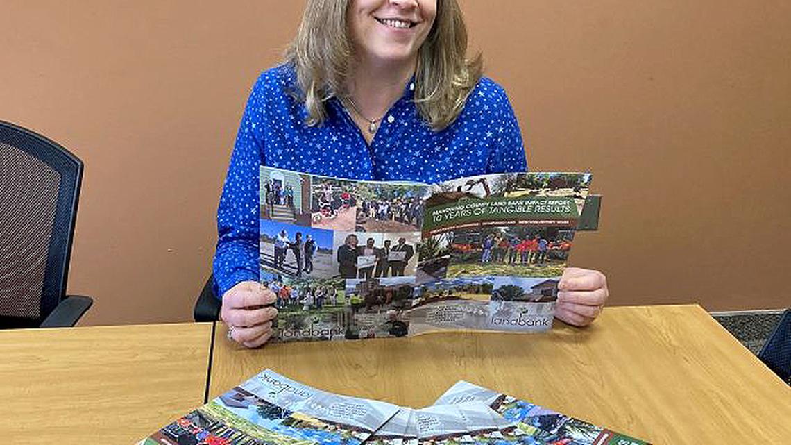 Debora Flora, Mahoning County Land Bank executive director, holds one of the first copies of the 10-year impact report. (Contributed photo)