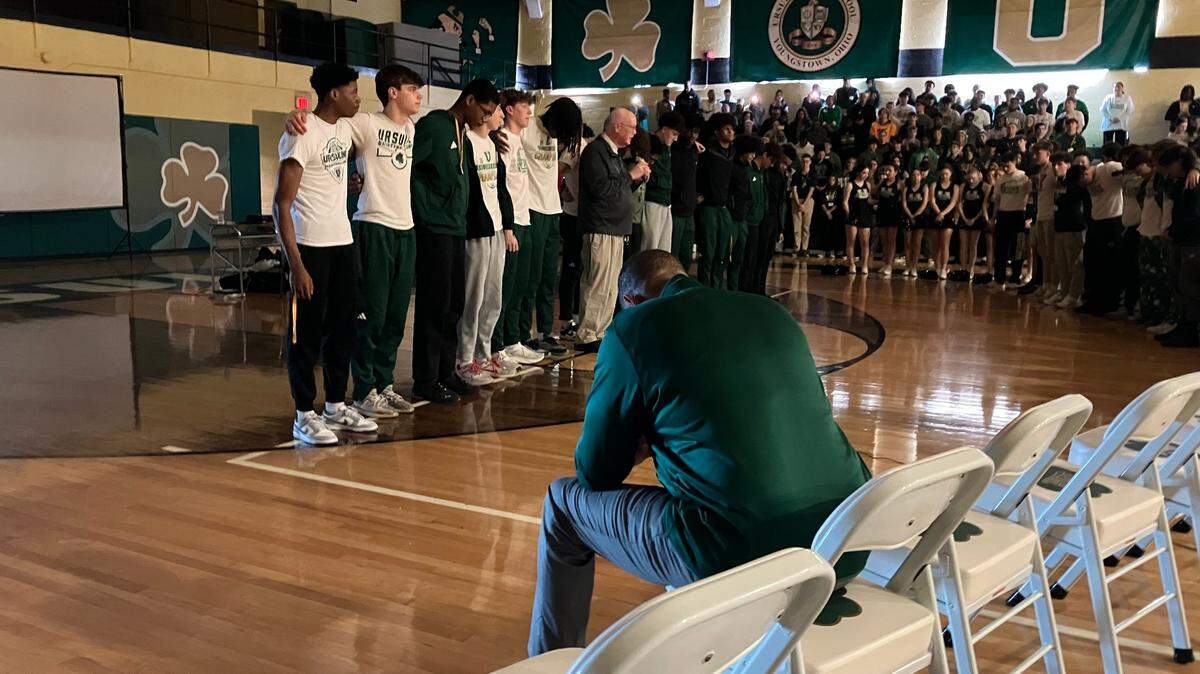 Youngstown Ursuline boys basketball coach Keith Gunther prays while his team prays with school president and chaplain Richard Murphy during a rally for the team before this weekend’s state basketball tournament.