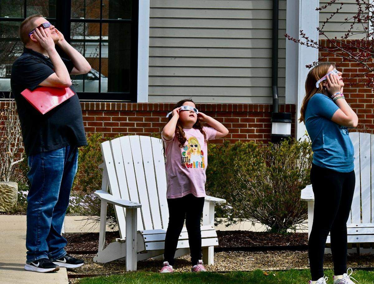 A family looks at the solar eclipse Monday during an event held at the Canfield branch of the Youngstown and Mahoning County Library.