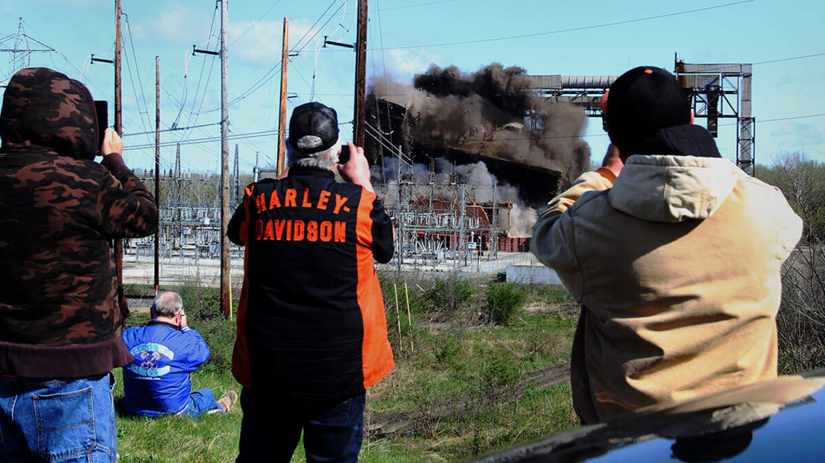 More than a dozen employees of the former Niles Generating Station along Belmont Avenue in Weathersfield Township watch as the structure is demolished on Thursday, April 28, 2022.