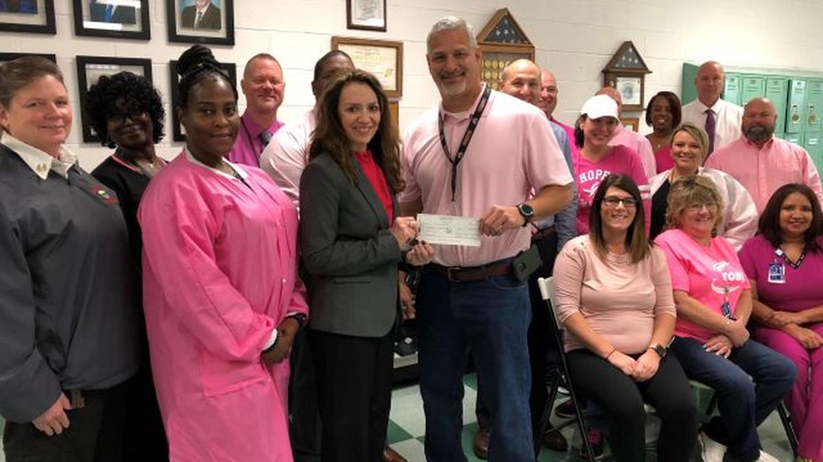 Warden Richard A. Bowen Jr. and employees at the Ohio State Penitentiary in Youngstown present a check to Gina Marinelli, of the Mercy Health Foundation, in support of the Joanie Abdu Comprehensive Breast Care Center. (Contributed photo)