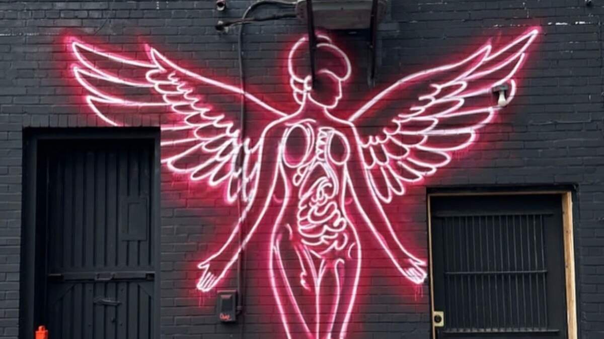 In order to achieve the neon light effect, Chine used pink spray paint that stands out on a black background, giving the wall a glow.